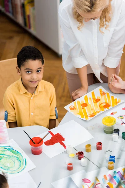 Overhead view of happy african american boy near teacher and kid — Stock Photo