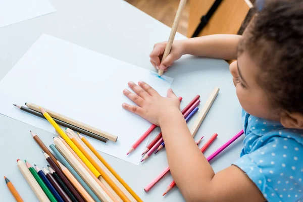 Вид зверху мила афроамериканська дитина малює на порожньому папері — стокове фото