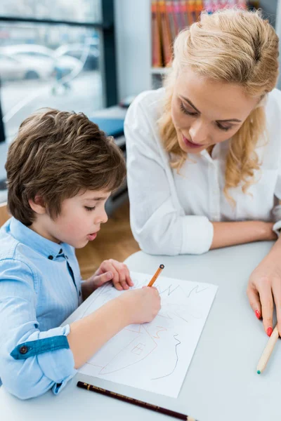 Messa a fuoco selettiva della donna guardando bambino carino disegno su carta — Foto stock