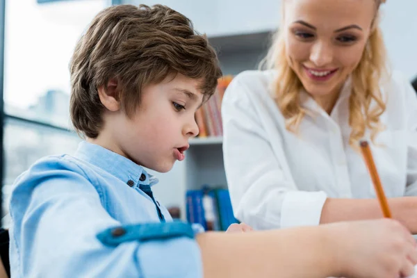 Selective focus of cute kid drawing near happy woman — Stock Photo