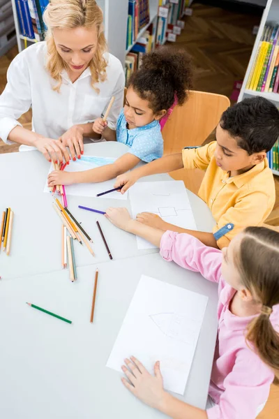 Vue aérienne d'une jolie femme assise avec des enfants multiculturels mignons — Photo de stock