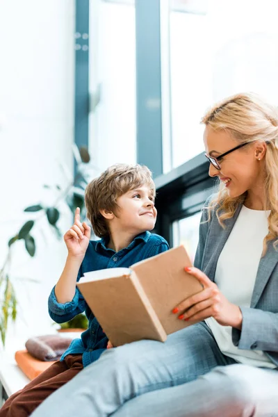 Cheerful woman in glasses looking at cute kid having idea — Stock Photo