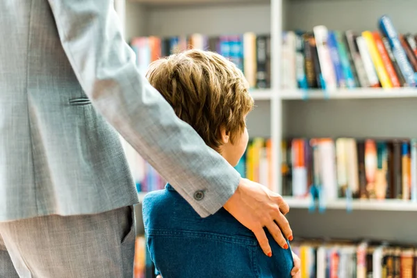 Vista recortada de la mujer de pie con el niño en la biblioteca - foto de stock