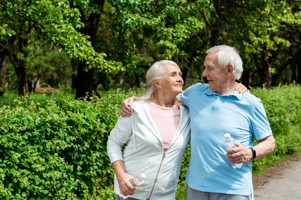 Alegre senior mujer con cerrado ojos cerca marido en parque - foto de stock