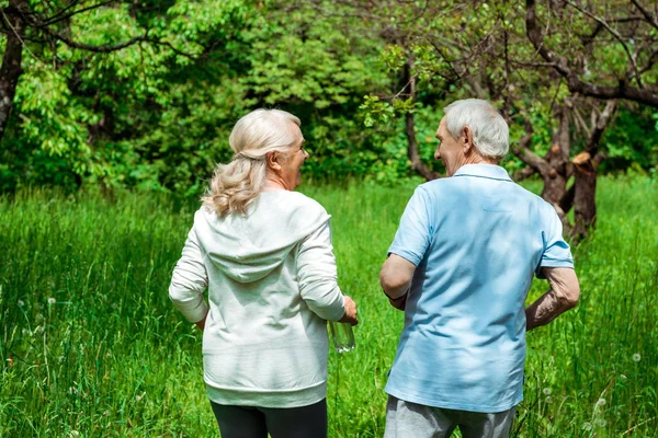 Donna anziana guardando il marito mentre corre nel parco verde — Foto stock