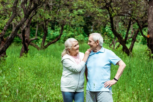 Fröhliche Seniorin sieht Ehemann mit Hand auf Hüfte stehen — Stockfoto
