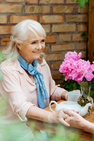 Selektiver Fokus der glücklichen Seniorin, die Händchen hält mit Ehemann — Stockfoto