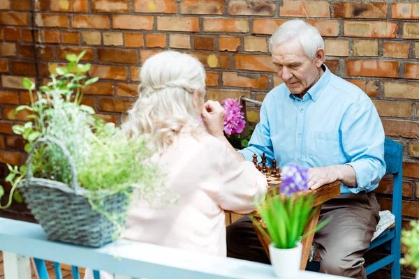 Selective focus of retired man and woman sitting near brick wall — Stock Photo