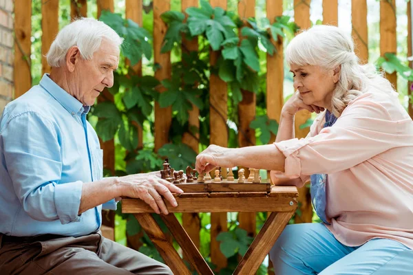 Retired woman with grey hair playing chess with senior husband — Stock Photo