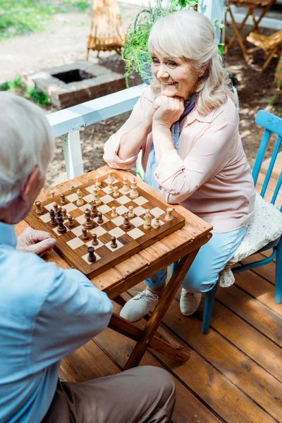 Вид зверху весела пенсіонерка, яка грає в шахи з старшим чоловіком — Stock Photo