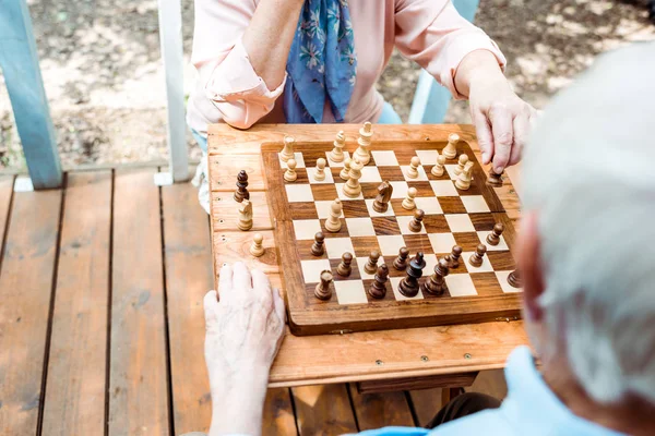 Vista recortada del hombre y la mujer jubilados jugando al ajedrez - foto de stock