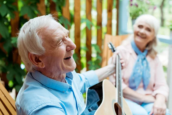 Selektiver Fokus des glücklichen Ehemanns, der neben der Seniorin Akustikgitarre spielt — Stockfoto