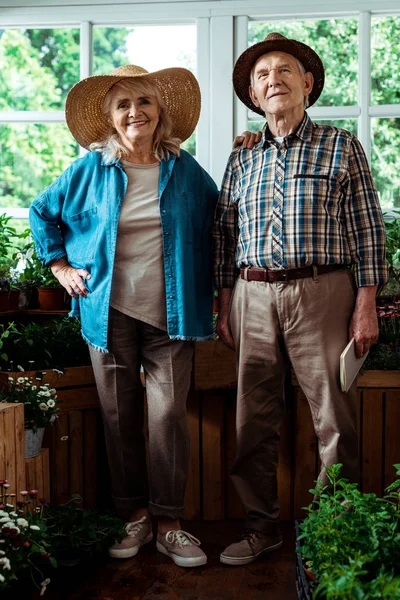 Selektiver Fokus eines glücklichen älteren Mannes, der sein Notizbuch in der Hand hält und mit seiner Frau steht — Stockfoto