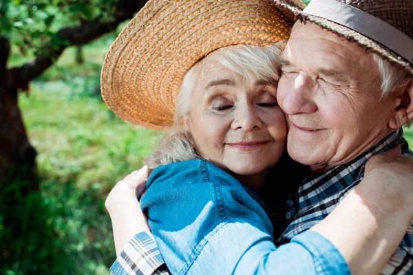 Cheerful senior woman hugging happy retired husband with closed eyes — Stock Photo