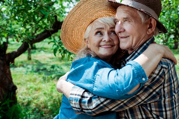 Cheerful senior woman hugging retired husband with closed eyes — Stock Photo