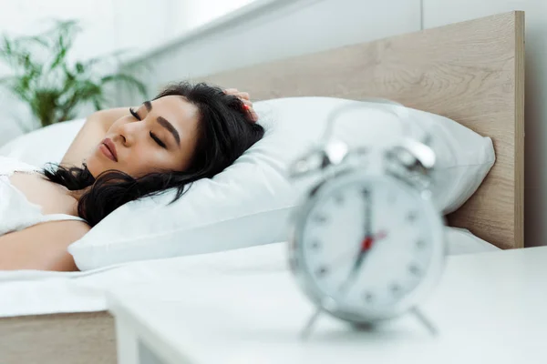 Selektiver Fokus der asiatischen Frau, die in der Nähe des Weckers schläft — Stockfoto