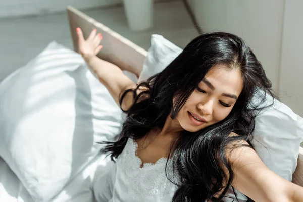 Overhead view of cheerful asian woman with closed eyes and outstretched hands — Stock Photo