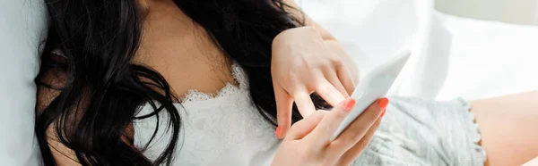 Panoramic shot of brunette woman using smartphone at home — Stock Photo