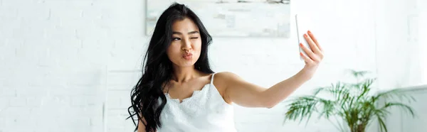 Plan panoramique de fille asiatique avec visage de canard prenant selfie sur smartphone — Photo de stock