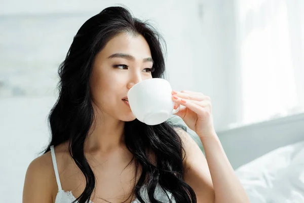 Atractiva morena tailandesa bebiendo té en casa - foto de stock