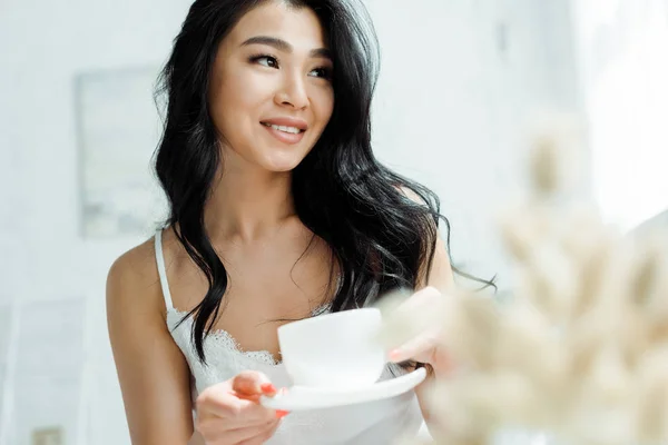 Enfoque selectivo de la mujer tailandesa positiva sosteniendo la taza con té - foto de stock
