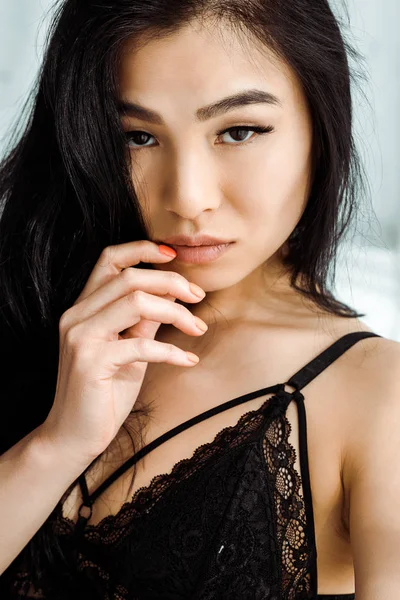 Sexy asiático mujer en encaje ropa interior de pie y tocar la cara - foto de stock