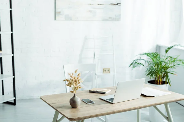 Portátil y smartphone con pantalla en blanco en la mesa de madera en la oficina moderna - foto de stock