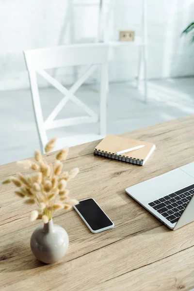 Fuoco selettivo di smartphone con schermo bianco vicino a computer portatile e notebook in ufficio — Foto stock