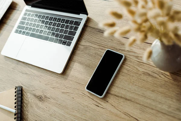 Селективный фокус смартфона с чистым экраном рядом с ноутбуком — стоковое фото