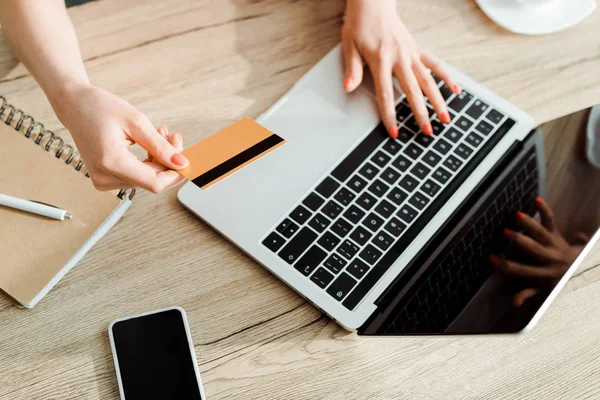 Vista ritagliata di giovane donna in possesso di carta di credito durante l'utilizzo del computer portatile — Foto stock