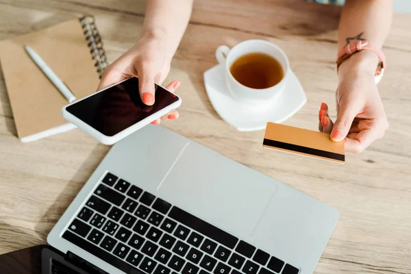 Vista recortada de la mujer sosteniendo teléfono inteligente con pantalla en blanco y tarjeta de crédito — Stock Photo