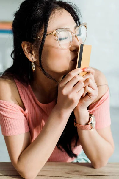 Attractive asian woman with closed eyes kissing credit card — Stock Photo