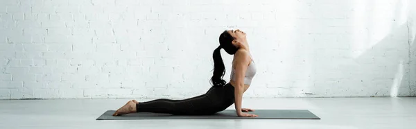 Plano panorámico de hermosa morena tailandesa haciendo ejercicio sobre esterilla de yoga - foto de stock