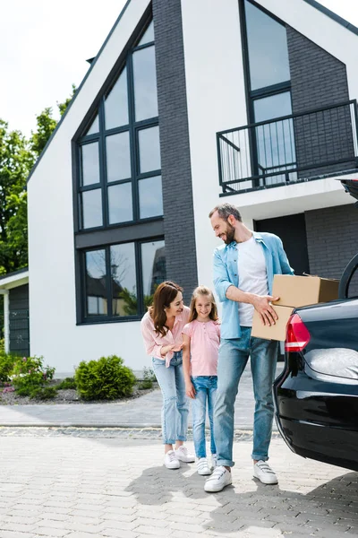 Happy man holding boxes near cheerful wife and kid — Stock Photo