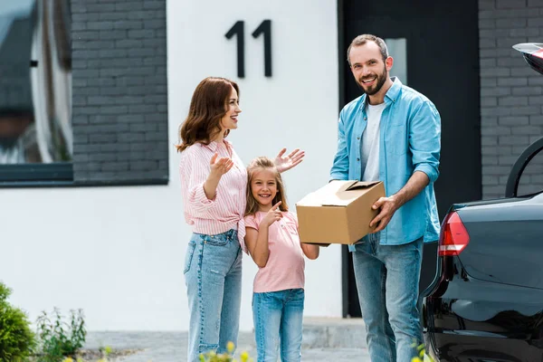 Cheerful and cute kid pointing with finger at father with box — Stock Photo
