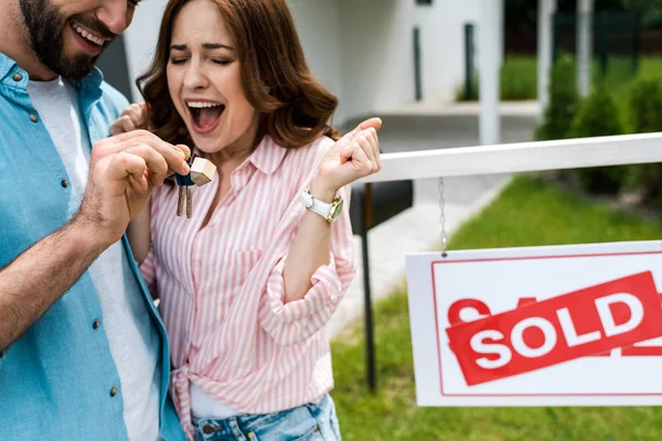 Ausgeschnittene Ansicht eines bärtigen Mannes mit Schlüssel in der Nähe eines aufgeregten Mannes — Stockfoto