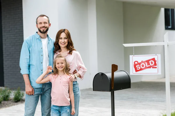 Homme heureux debout avec femme et fille près de la maison et la pension avec des lettres vendues — Photo de stock