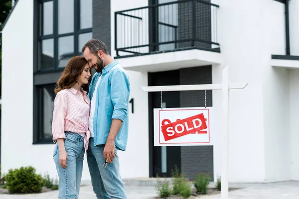 Feliz hombre y mujer con los ojos cerrados de pie cerca de la casa - foto de stock