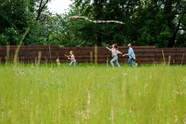 Foyer sélectif de mignon enfant en cours d'exécution avec cerf-volant coloré près des parents — Photo de stock