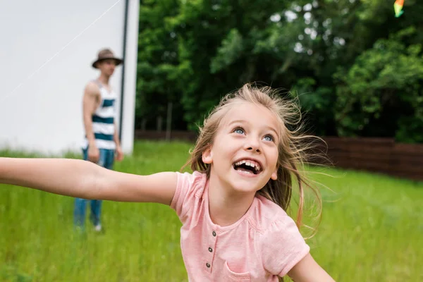 Избирательный фокус счастливого ребенка, улыбающегося рядом с отцом снаружи — стоковое фото