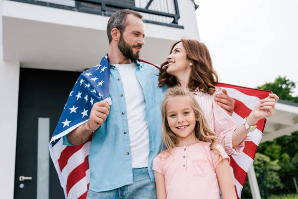 Vista angolo basso del bambino felice vicino ai genitori allegri con bandiera americana — Foto stock