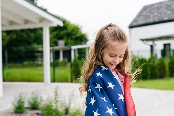 Glückliches Kind steht mit amerikanischer Flagge in der Nähe von Haus — Stockfoto