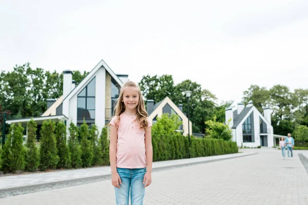 Cheerful kid smiling white standing on street near houses — Stock Photo