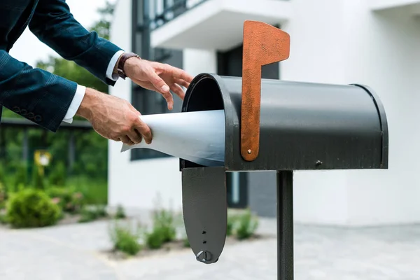 Cropped view of man putting blank paper in mail box near house — Stock Photo