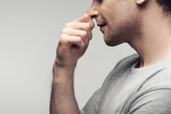 Partial view of pensive man touching nose isolated on grey, human emotion and expression concept — Stock Photo