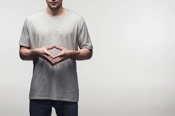 Partial view of man in grey t-shirt showing steeple gesture while using body language isolated on grey, human emotion and expression concept — Stock Photo