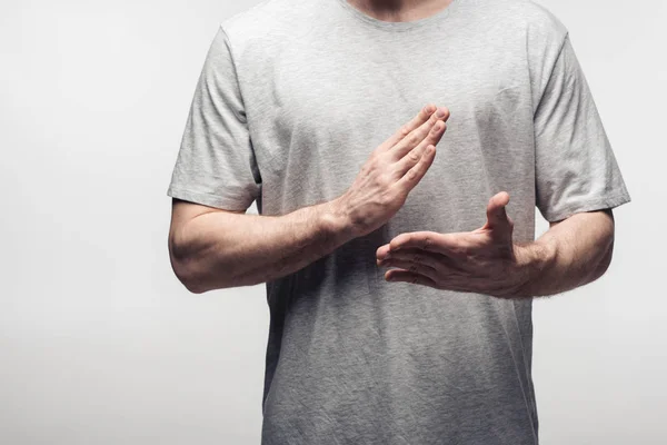 Vista recortada del hombre haciendo gestos con las manos mientras utiliza el lenguaje corporal aislado en gris, emoción humana y concepto de expresión - foto de stock