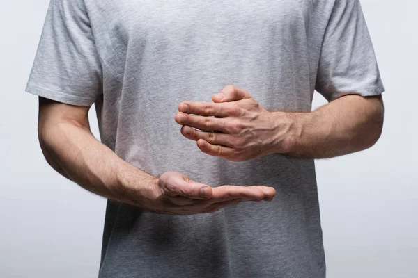 Visión parcial del hombre haciendo gestos con las manos mientras utiliza un lenguaje corporal aislado en gris, emoción humana y concepto de expresión - foto de stock