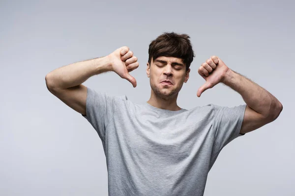 Uomo scontento mostrando pollici verso il basso isolato sul grigio, emozione umana e concetto di espressione — Foto stock