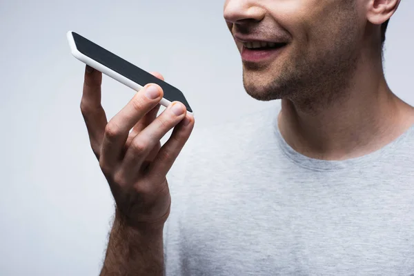 Partial view of smiling man using smartphone isolated on grey — Stock Photo